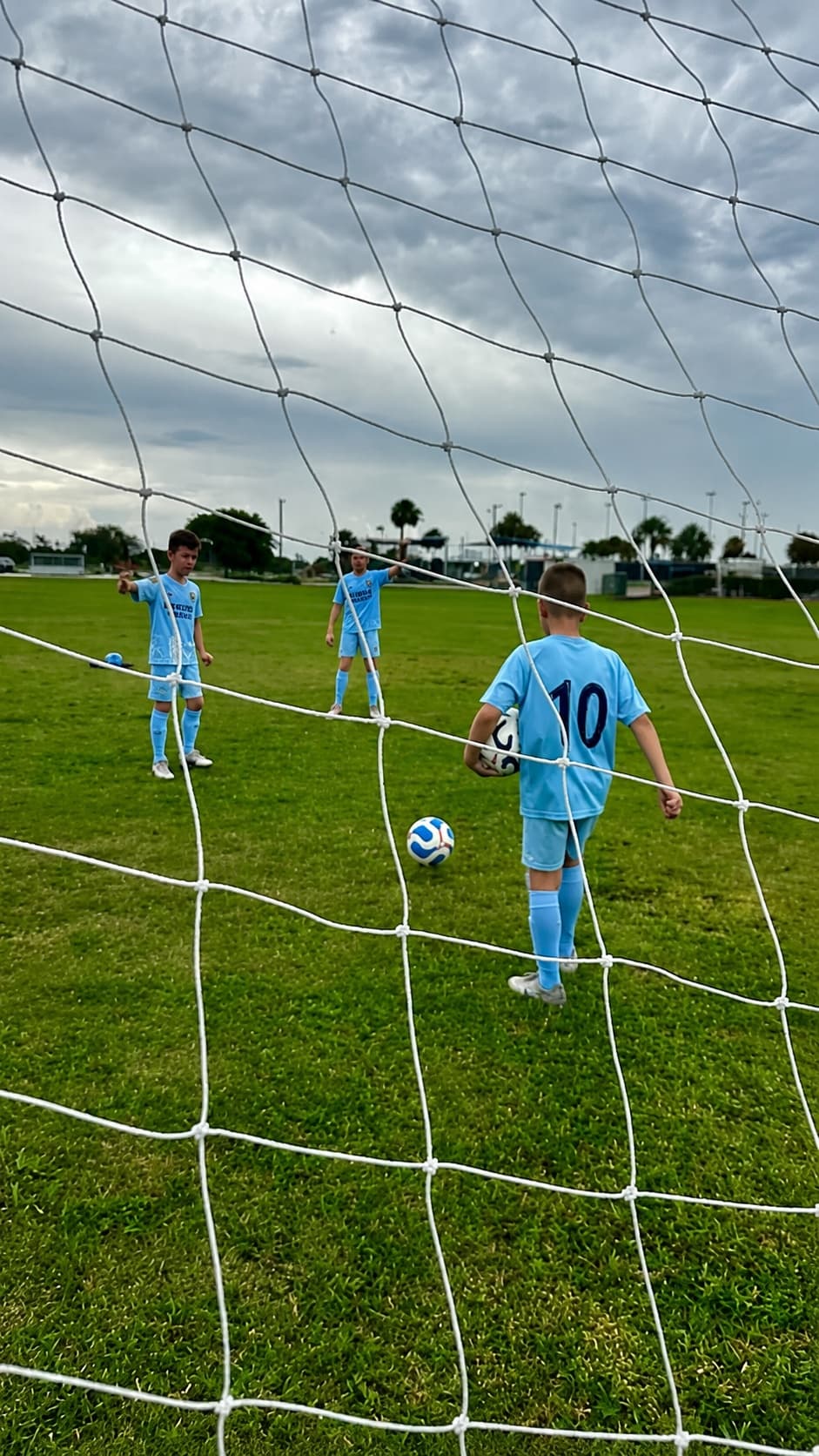 Kraken Academy players training on the pitch, seen through the goal net