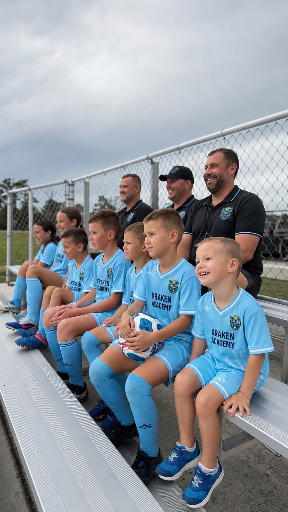Kraken Academy players and coaches sitting along the bleachers, laughing